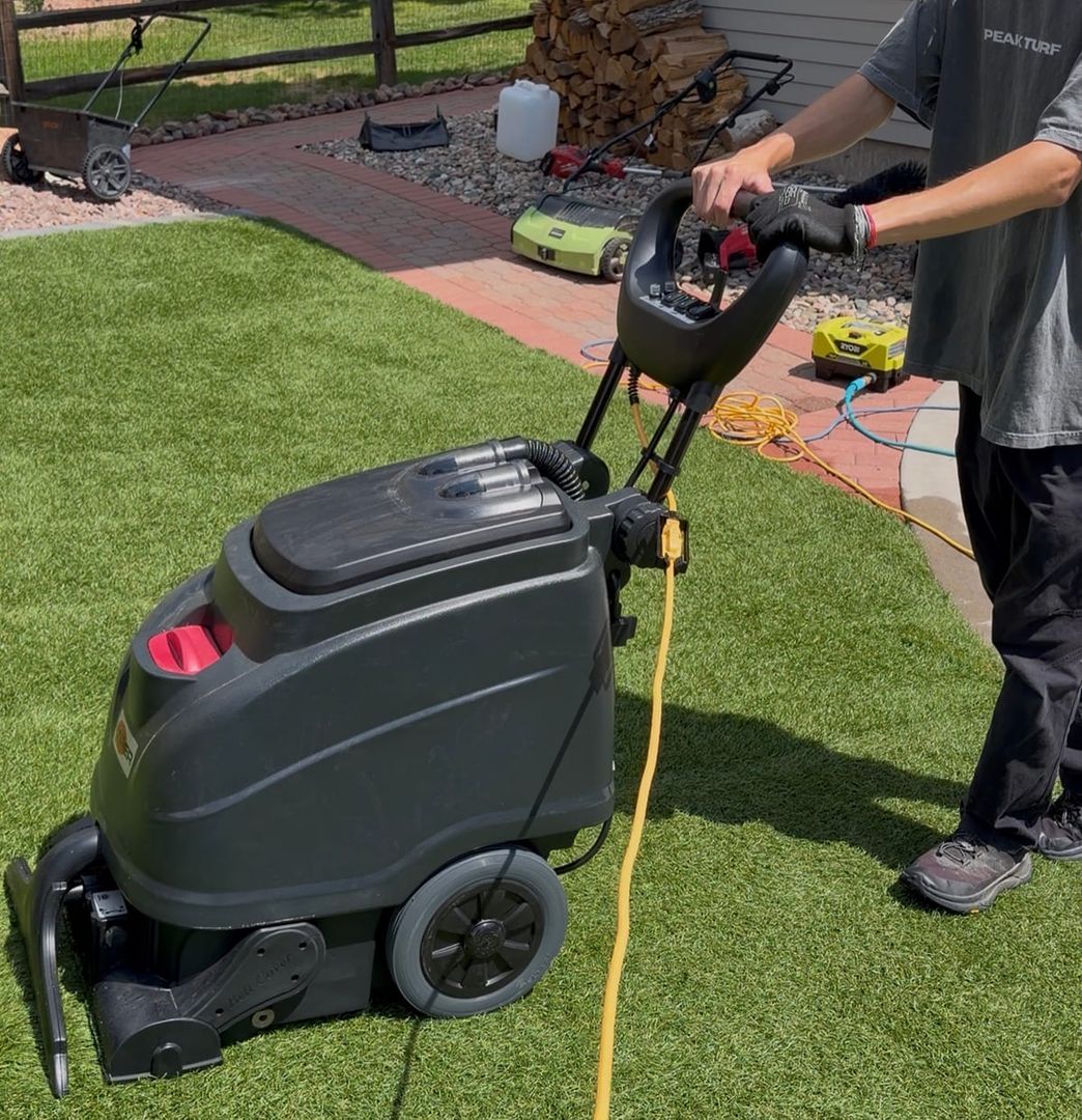 Peak Turf Solutions technician running a commercial extractor across artificial turf in Colorado Springs